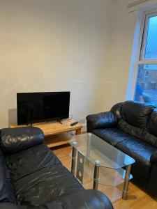 - un salon avec deux canapés en cuir et une télévision dans l'établissement Nice House Near QMC, à Nottingham