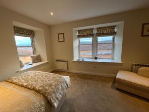 a bedroom with two windows and a bed at Tomdoun Estate in Invergarry