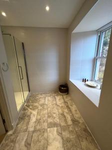 a bathroom with a shower and a tiled floor at Tomdoun Estate in Invergarry