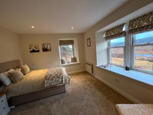 a bedroom with a bed and two windows at Tomdoun Estate in Invergarry