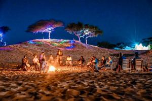 Un groupe de gens autour d'un feu sur une plage la nuit dans l'établissement Camp Rêve de Nomade, à Lompoul