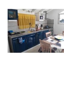 Anse-Bertrand的住宿－Haut de villa agréable et paisible climatise, wifi，厨房配有蓝色橱柜和餐桌