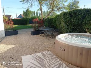 una bañera de hidromasaje en un patio trasero con mesa y sillas en La Cosy, en Lancé