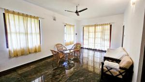a living room with a table and chairs and windows at Nature full Resort in Masinagudi