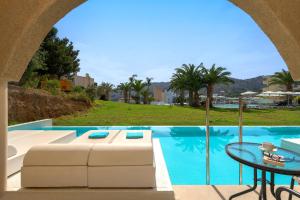 a swimming pool with a table and a couch and a table at Lindos Royal Resort in Líndos