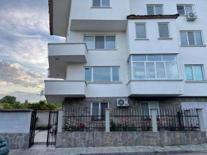 een wit gebouw met een hek ervoor bij ЛАЗАРОВИ in Hisarya