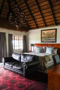 a bedroom with a bed and a leather couch at Lucca Lodge in Musina