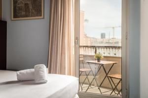 a bedroom with a bed and a balcony with a table at Hotel Madanis in Barcelona