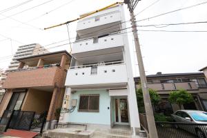 una casa blanca en una calle con un poste en あやきちゲストハウス, en Daikōchō