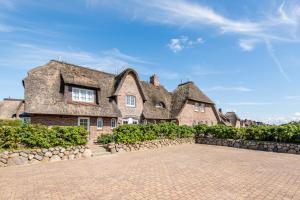 a large stone house with a large roof at Haus Raanwai Whg 3a in Rantum