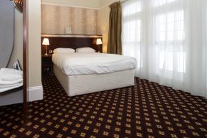 um quarto de hotel com uma cama grande e janelas em Cabot Court Hotel Wetherspoon em Weston-super-Mare