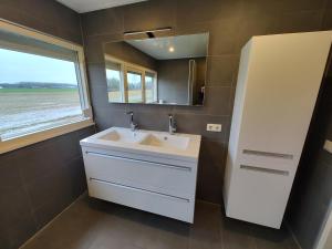 baño con lavabo blanco y ventana en 8 person farmhouse with sauna, en Toldijk