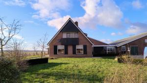 ein Backsteinhaus mit einem grünen Hof in der Unterkunft 8 person farmhouse with sauna in Toldijk