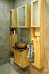 a bathroom with a sink and wooden cabinets at Gîte-Spa Nature in Urschenheim