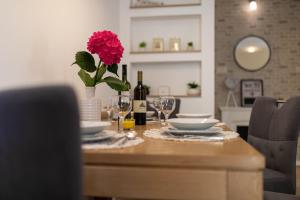 drewniany stół z wazonem kwiatów i butelkami wina w obiekcie Apartment Marangunija w mieście Malinska