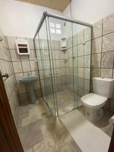 a bathroom with a shower and a toilet and a sink at Pousada Marinheiro in Sítio