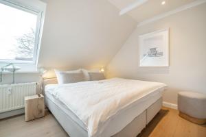 um quarto com uma cama branca e uma janela em Strandbude Sylt em Westerland