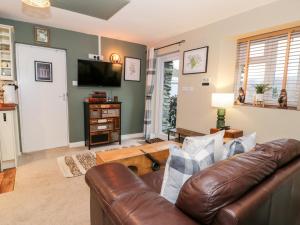 een woonkamer met een leren bank en een televisie bij Cwm Caeth Cottage in Caernarfon
