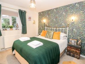 een slaapkamer met een bed met groene en oranje kussens bij Cwm Caeth Cottage in Caernarfon