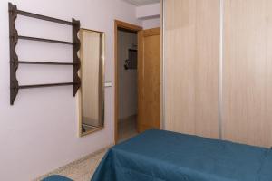 een kamer met een spiegel, een bed en een deur bij Amador, 3º-J in Cullera