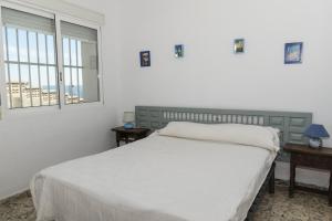 a white bedroom with a bed and two windows at Hawai Bajo in Faro de Cullera
