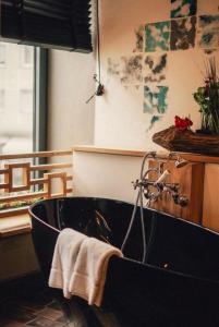 eine schwarze Badewanne im Bad mit Fenster in der Unterkunft 36 Phô Cô Hotel & Suites in Weimar