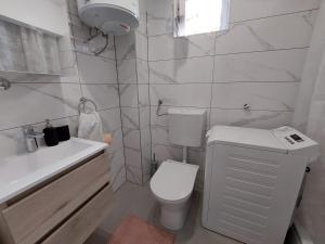 a white bathroom with a toilet and a sink at Apartments Timee first row to beach in Stanići +15 photos