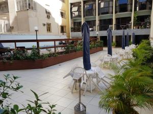 a patio with white chairs and blue umbrellas at Duplex charmoso - Ótima localização in Rio de Janeiro