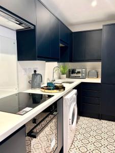 a kitchen with blue cabinets and a washing machine at Studios 21- By Eazy Rooms in Hessle