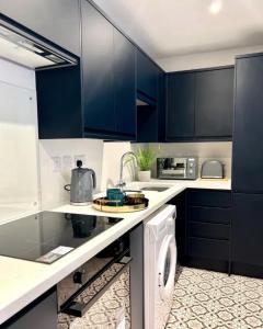 a kitchen with blue cabinets and a washing machine at Studios 21- By Eazy Rooms in Hessle