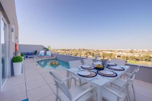 una mesa blanca y sillas en un balcón con piscina en Salmar Court Holiday Apartments, en Hal Ghaxiak