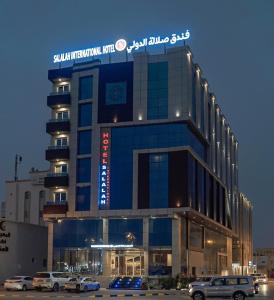 Salalah International Hotel في صلالة: مبنى كبير به سيارات تقف في موقف للسيارات