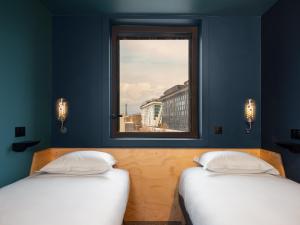 two beds in a room with a window at Eklo Paris Expo Porte de Versailles in Vanves