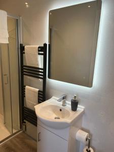 a bathroom with a white sink and a mirror at Glan Y Mor Hotel (Adult Only) in Llandudno