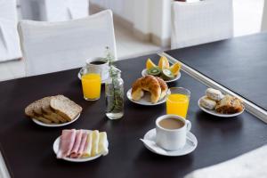 a table topped with plates of breakfast foods and orange juice at SH Hotel & Spa de Mar Samay Huasi in Puerto Madryn