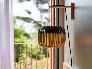 a black and yellow lamp in front of a window at ibis Thalassa Hyeres Plage in Hyères