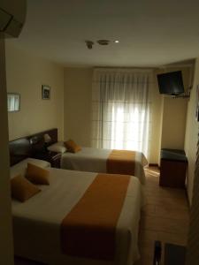 a hotel room with two beds and a television at Hotel Complutense in Alcalá de Henares