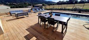 een houten terras met een tafel en stoelen naast een zwembad bij Élégance Corse : Maison 3 chambres, Piscine in Figari