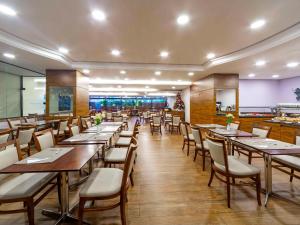 comedor con mesas y sillas de madera en Mercure Curitiba Golden, en Curitiba