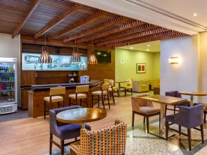 a restaurant with tables and chairs and a bar at Mercure Curitiba Golden in Curitiba