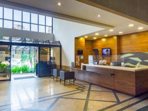 un hall avec un comptoir et des chaises dans un bâtiment dans l'établissement Mercure Curitiba Golden, à Curitiba