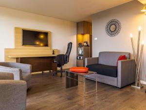 a living room with a couch and a chair at Novotel Senart Golf De Greenparc in Saint-Pierre-du-Perray