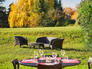 3 Stühle und ein Tisch mit Weingläsern drauf in der Unterkunft Novotel Senart Golf De Greenparc in Saint-Pierre-du-Perray