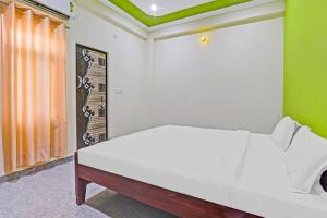 a bedroom with a white bed and a green wall at OYO Shiv Palace in Lucknow