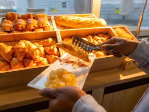 a person is getting food from a buffet at ibis Besançon Centre la City in Besançon