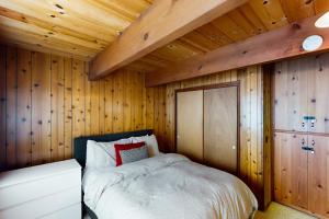 ein Schlafzimmer mit einem Bett in einer Holzwand in der Unterkunft Ward Creekside Cabin in Tahoe City