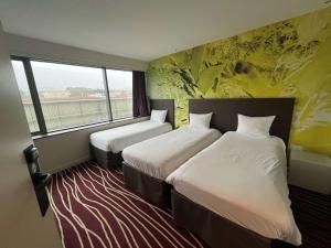 um quarto de hotel com duas camas e uma janela em ibis Styles Saint Julien en Genevois Vitam em Neydens