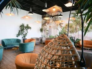 una hall con divani, tavoli e piante di ibis Styles Saint Julien en Genevois Vitam a Neydens