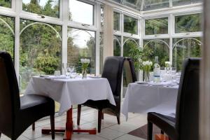 a dining room with two tables and chairs and windows at Best Western Claydon Hotel in Ipswich