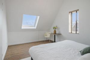 a white room with a bed and a table and a window at Vakantiehuis - Albert Aylerstraat 10 - Middelburg in Middelburg